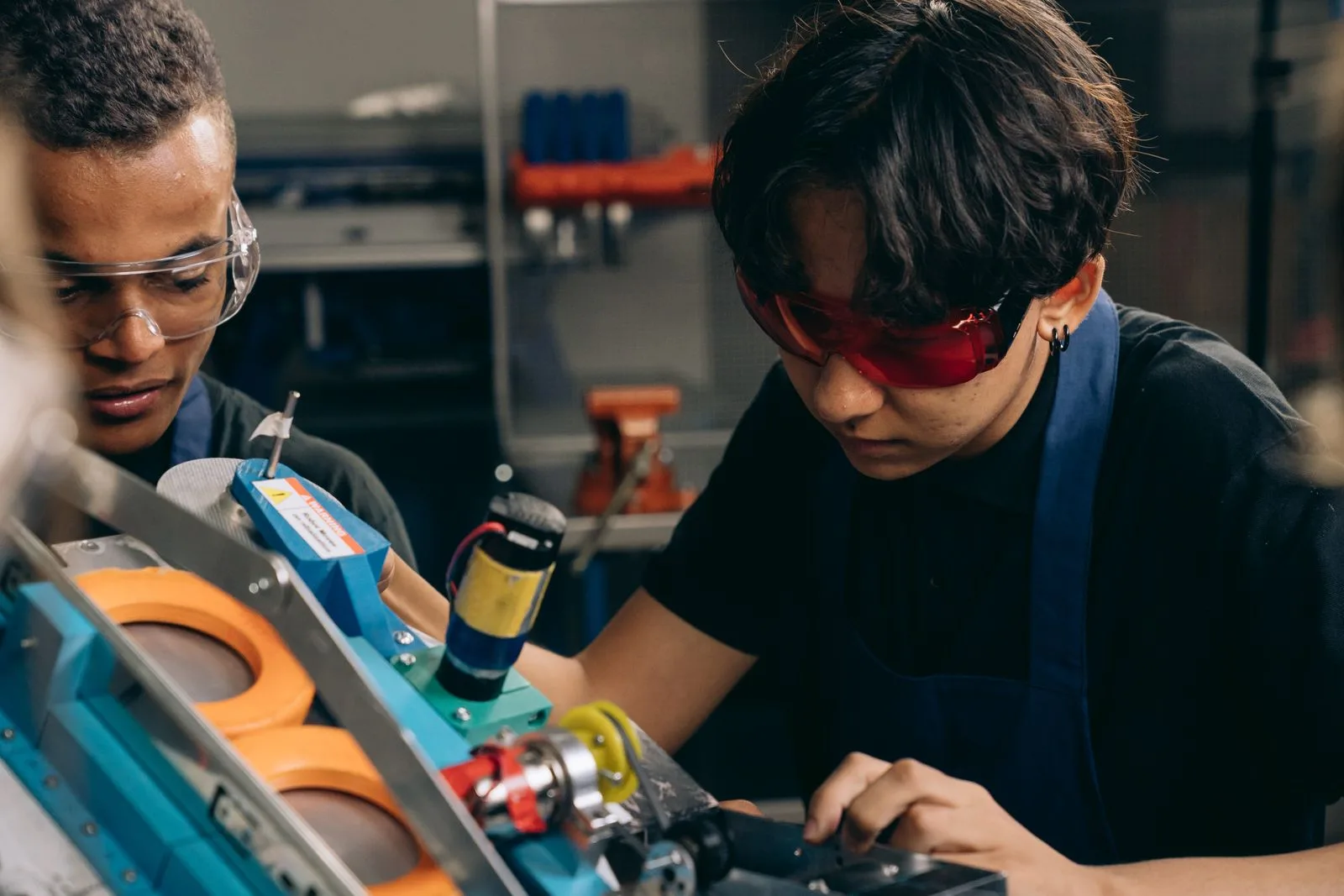 Two workers wearing safety goggles operating machinery in a manufacturing workshop