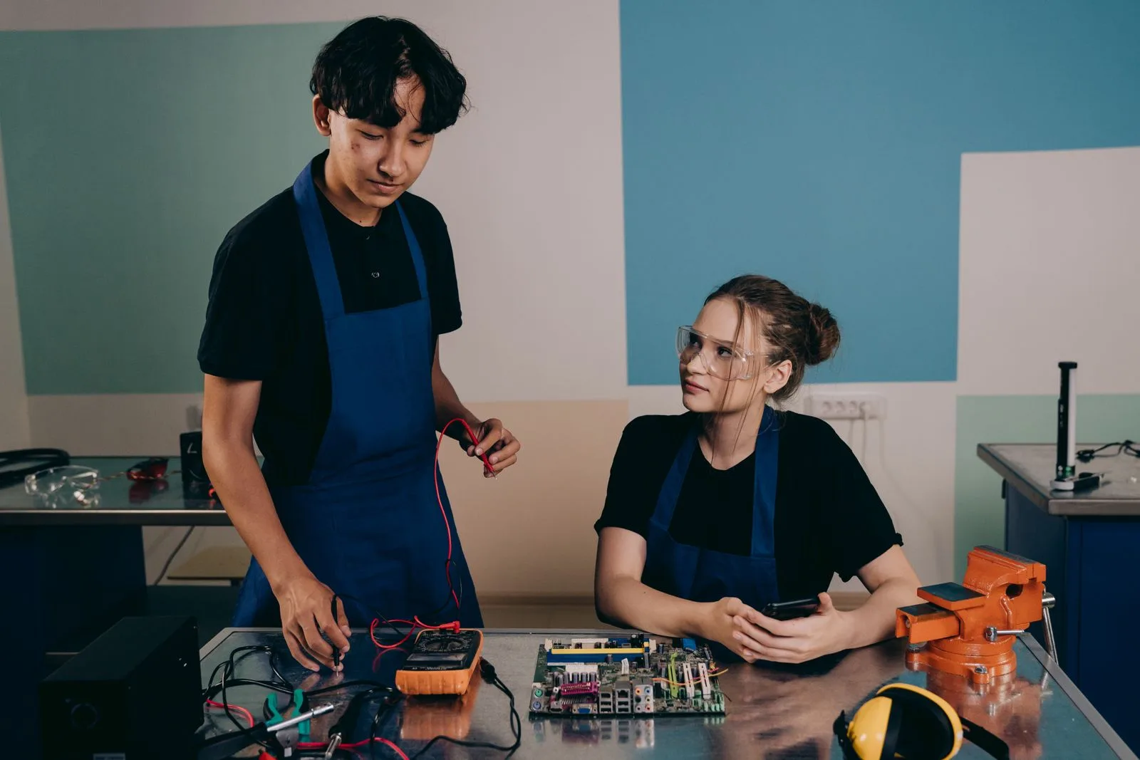 A technician and colleague fixing an electronic device on a workbench