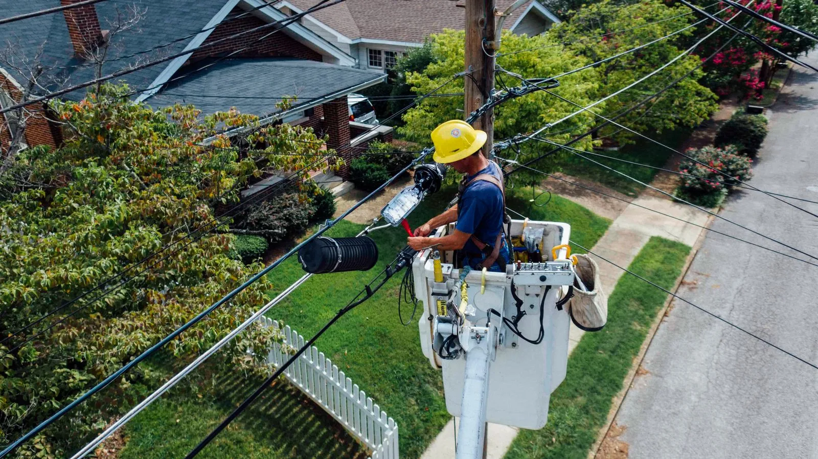 A utility worker repairing electrical wires on a pole