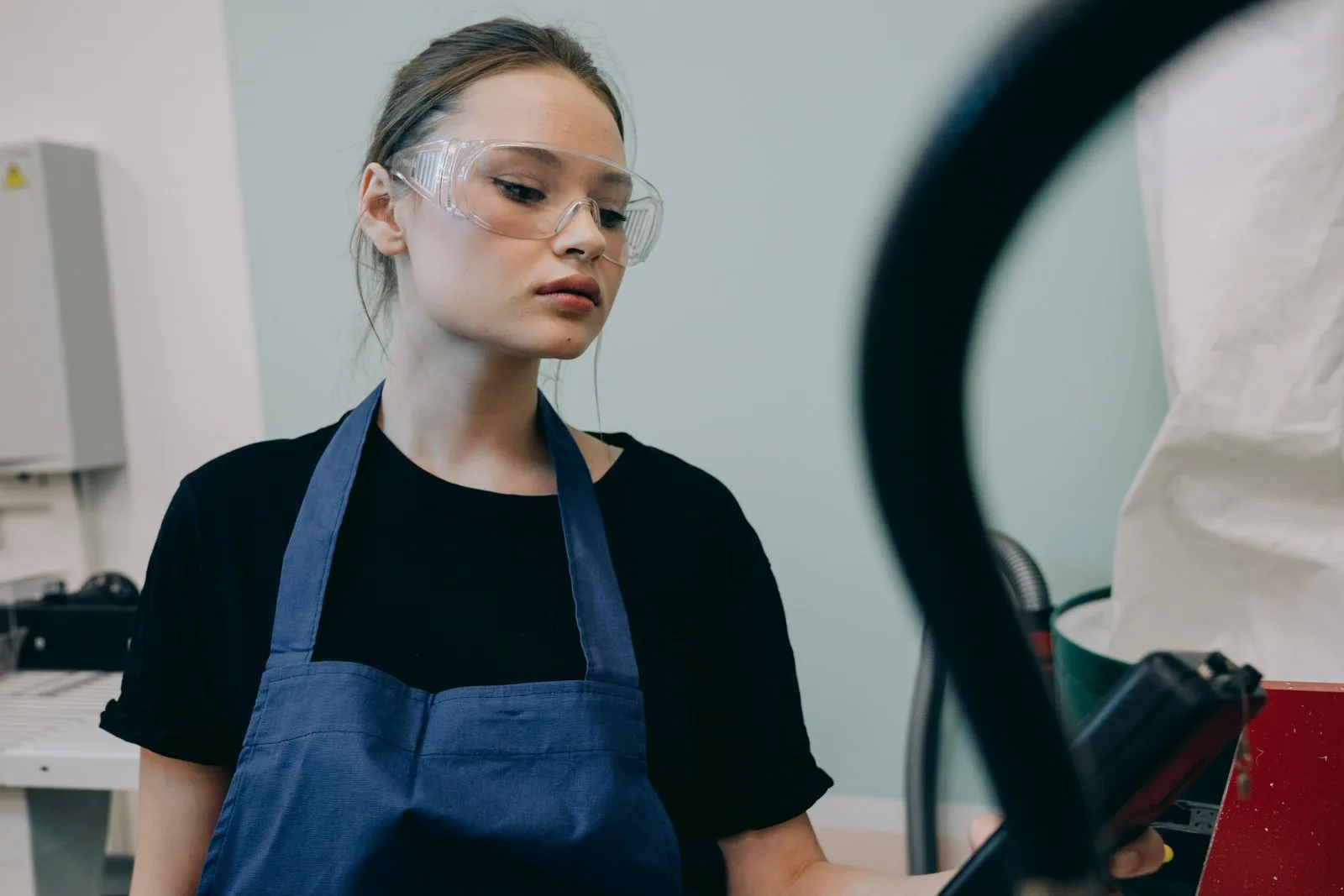 Worker in a blue apron wearing protective safety goggles