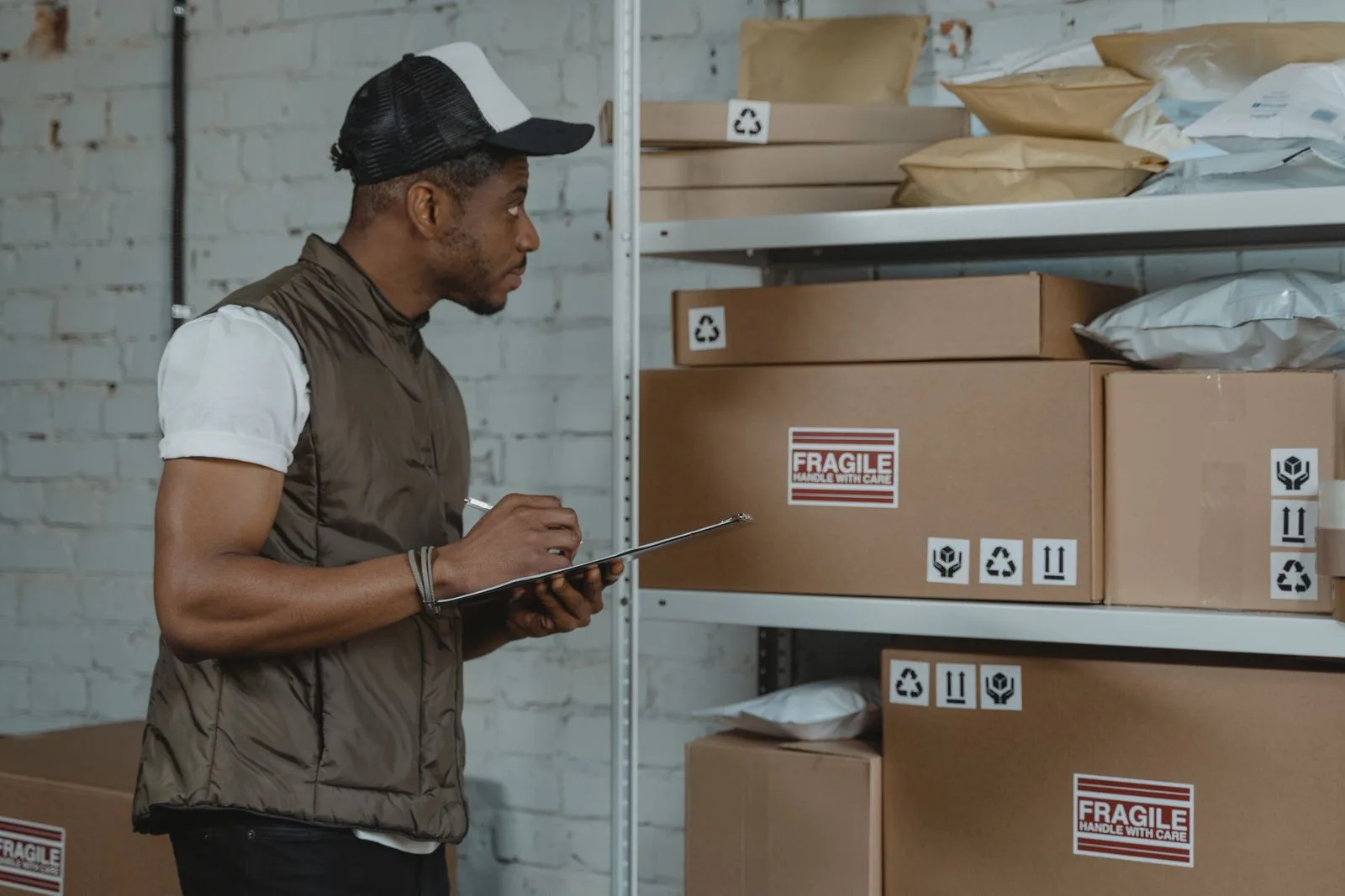 A warehouse worker taking inventory notes on a clipboard beside stocked shelving