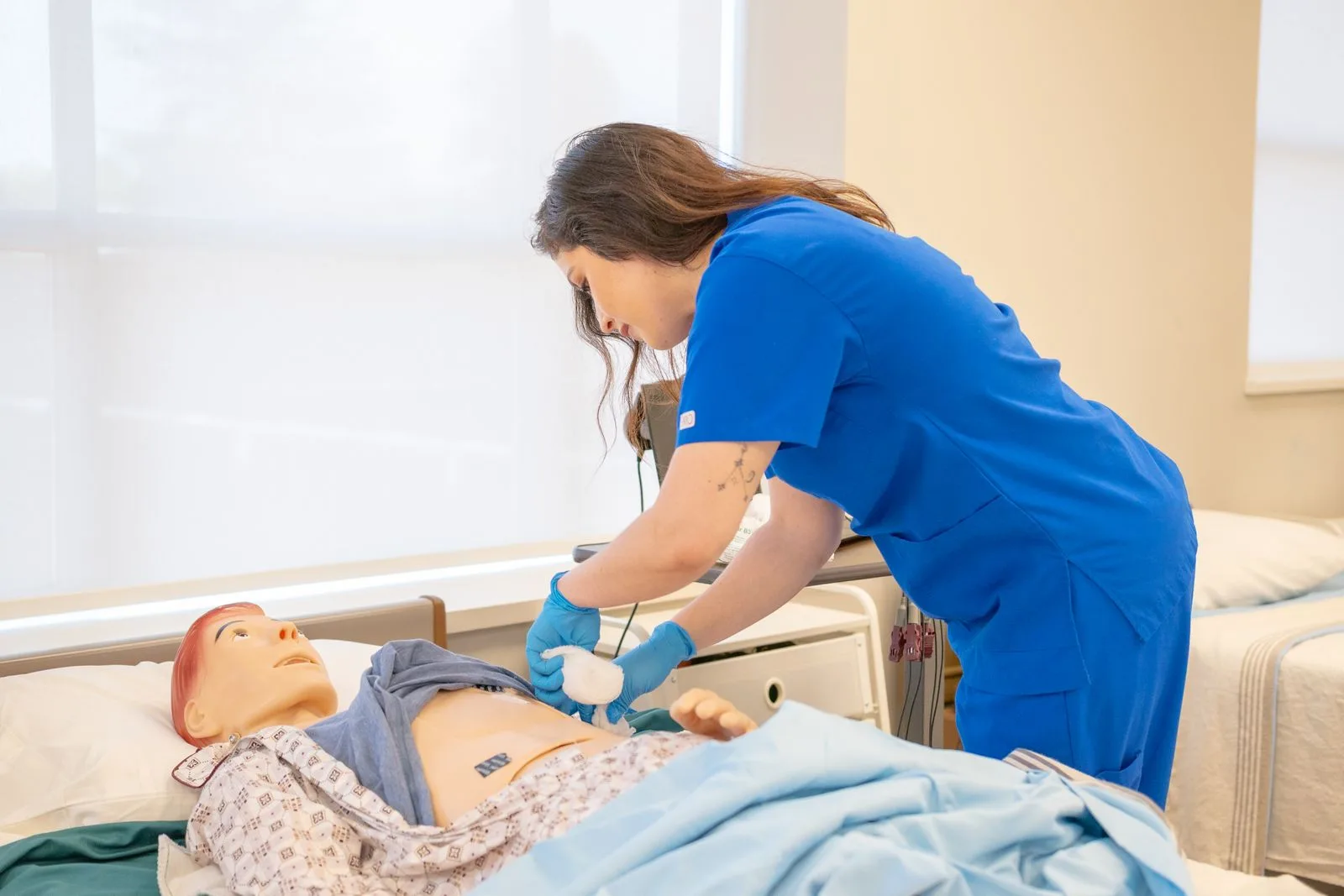 A nurse practicing procedures on a medical training manikin